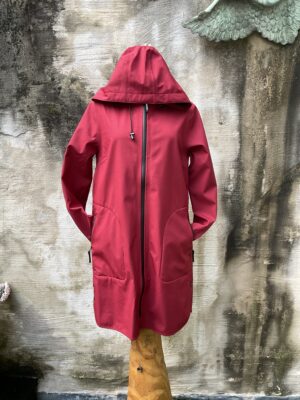 Rode, ademende regenjas van Ilse Jacobsen. A-lijn model met gelaste naden, grote zakken en afneembare kap