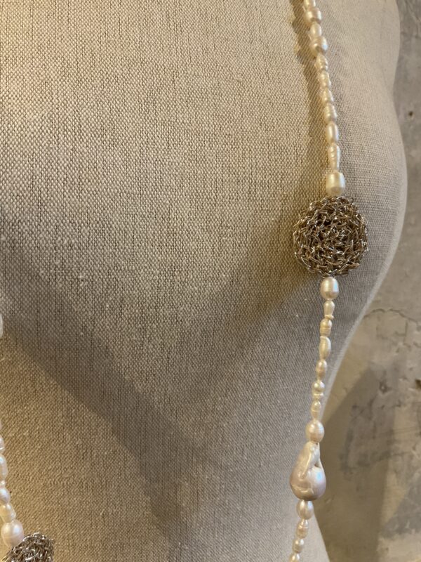 Grote maten mode Gent vrouwen kledij en accessoires dames. Lange halsketting met parels uit parelmoer en zilverkleurige gehaakte details van het Griekse juwelenmerk Taim.