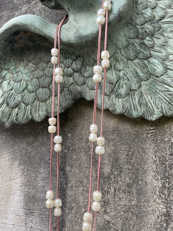 Grote maten mode Gent dames kledij vrouwen. Lange halsketting met magnetische sluiting van het Griekse juwelenmerk Taim. De collier bestaat uit twee lange roze geweven touwen met witte glanzende parels.