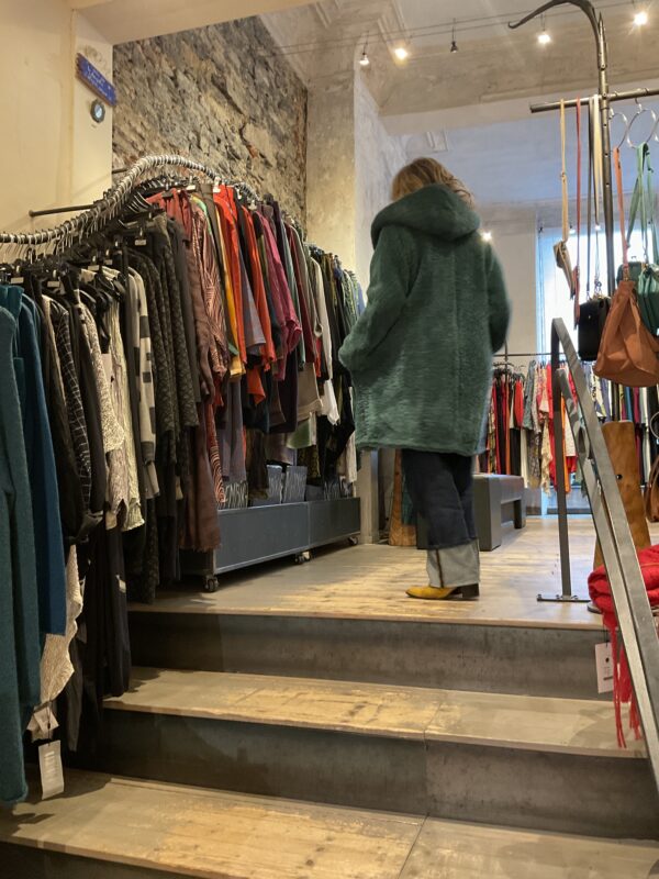 Grote maten mode Gent dames kledij en accessoires vrouwen. Middellange mantel met grote kap in blauw groene stof met wol en zelfde kleur voering van Fox’s