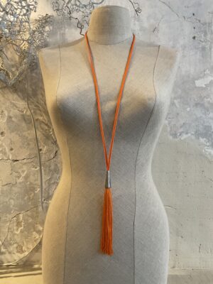 Grote maten mode Gent dames kledij en accessoires vrouwen. Lange halsketting, in lengte verstelbaar in oranje touw met zilverkleurig detail en grote oranje kwast van het Griekse juwelenmerk Taim