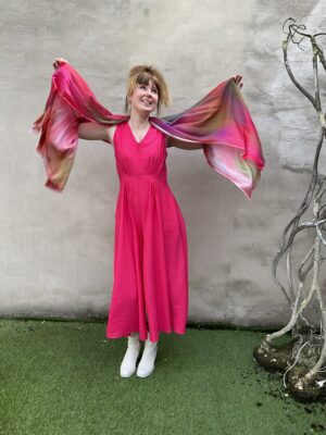 Grote maten mode Gent dames kledij en accessoires vrouwen. Fuchsia roze jumpsuit zonder mouwen met rits van Fox’s. Meerkleurige sjaal met streepjesmotief in diverse kleuren als paars, fuchsia, groen en oker geel.