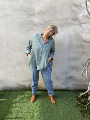 Kleurrijke, creatieve en aparte mode voor vrouwen in Gent. Halflange blouse in groen grijs linnen stof. De blouse heeft een kraagje, knoopjes en driekwart mouwen en loopt wijd uit. Blouse komt uit de tijdloze Grizas collectie