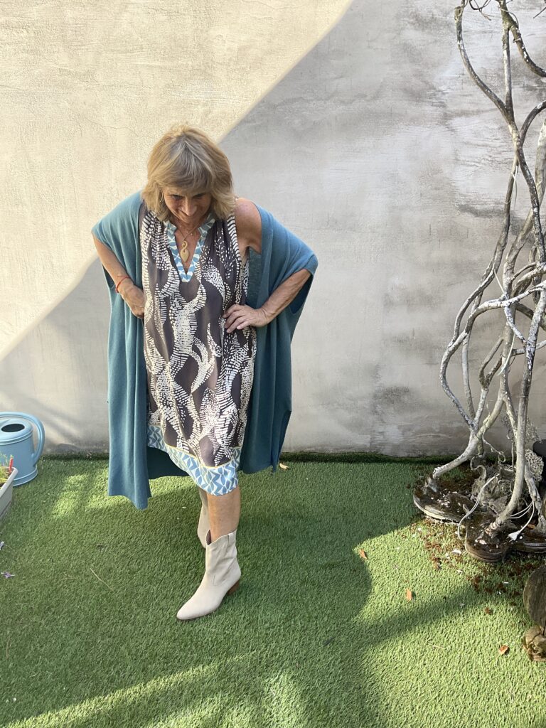Kleurrijke, creatieve en unieke mode voor dames in Gent. Grote maten mode dames kledij en accessoires voor vrouwen met een maatje meer of minder. Mouwloze jurk met mooie V-hals in print met bruin, blauw en beige van FOX’s. Lange open cardigan in petrol blauwe kleur met korte mouw van Bonita Avenue.