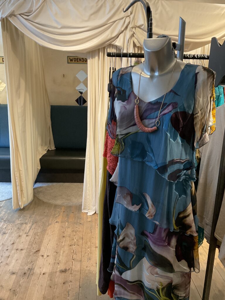 Kleurrijke, creatieve en aparte mode voor vrouwen in Gent. Grote maten mode dames kledij en accessoires voor vrouwen met een maatje meer of minder. Lange jurk in bedrukte zijde met korte transparante mouw van de Deense ontwerpster Tone Barker